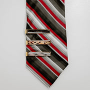 Striped tie with three gold tie clips on a light gray background
