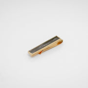 Gold tie clip with lionfish pelvic fin inlay on a gray background. 