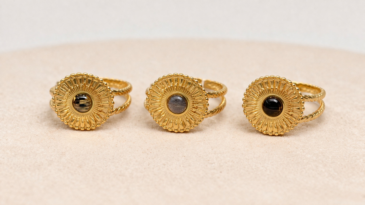 Three gold rings with lionfish fins on a beige surface