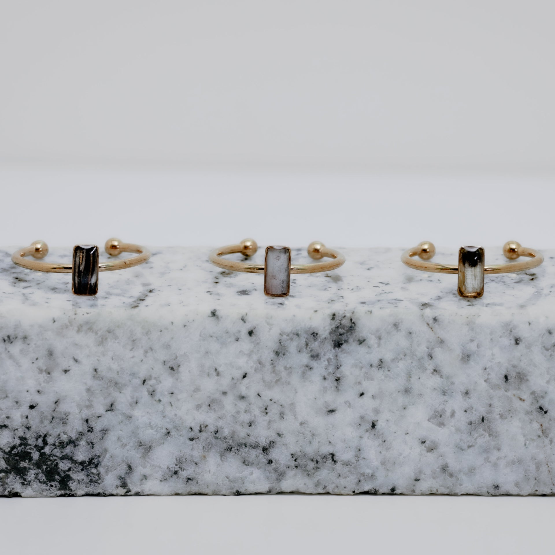 Three Gold rings with a small vertical bar on white and black marble on a white background