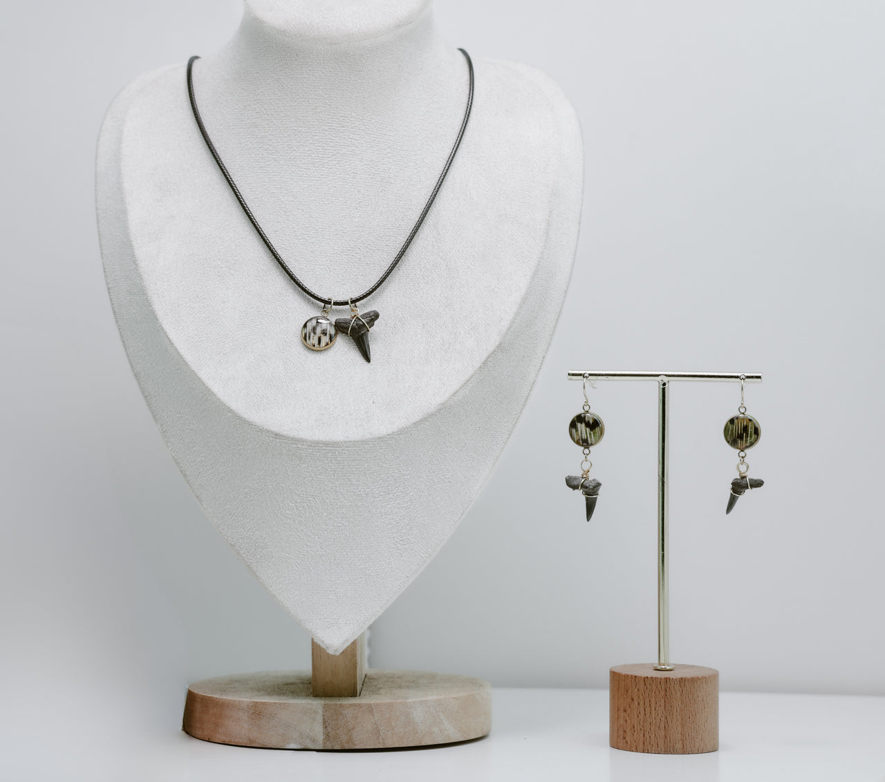 Necklace and earrings on a mannequin and stand against a white background