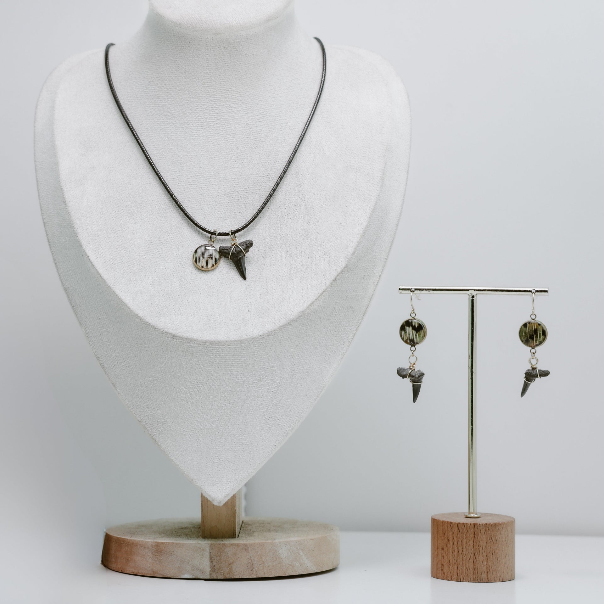 Necklace and earrings on a mannequin and stand against a white background