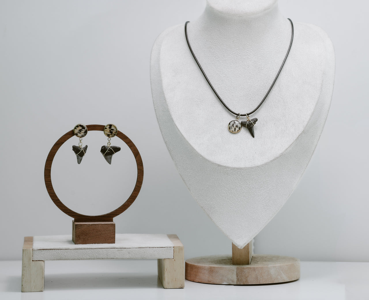 Jewelry set with earrings and a necklace on display stands against a white background