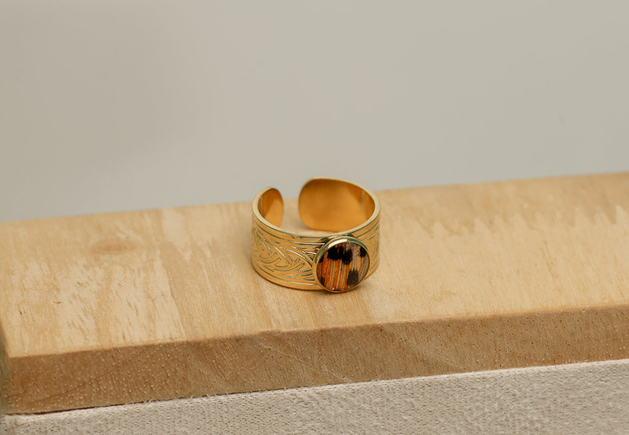 Gold lionfish ring with intricate design on a wooden surface