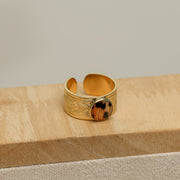 Gold lionfish ring with intricate design on a wooden surface