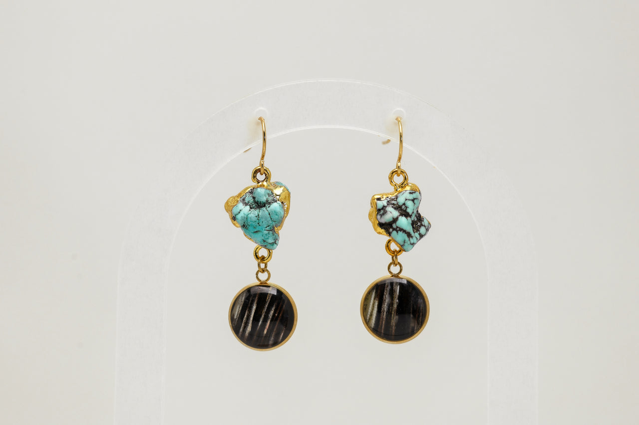 Pair of earrings with turquoise and black lionfish fins on a white background