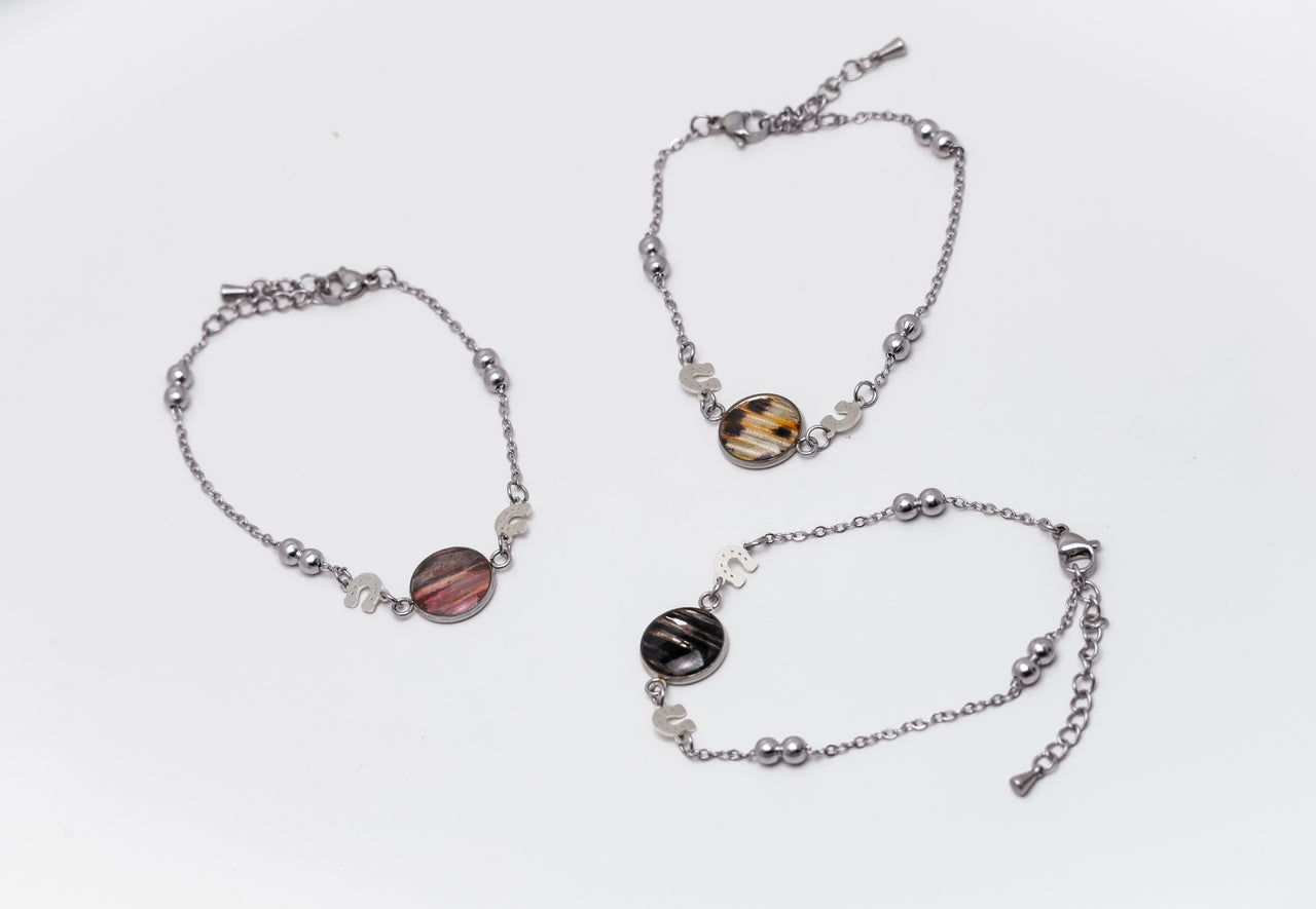 Three silver bracelets with lionfish fins on a white background