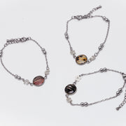 Three silver bracelets with lionfish fins on a white background