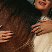 Close-up of hands on horse wearing lionfish rings and earrings in western-inspired styling