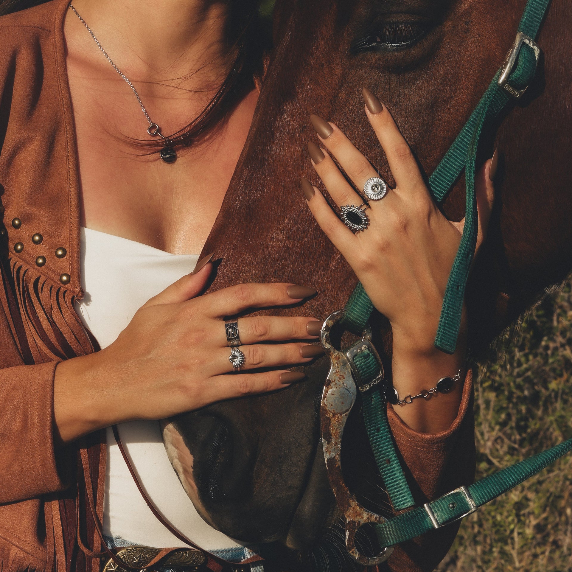 Person wearing multiple rings on a horse, with a focus on jewelry.