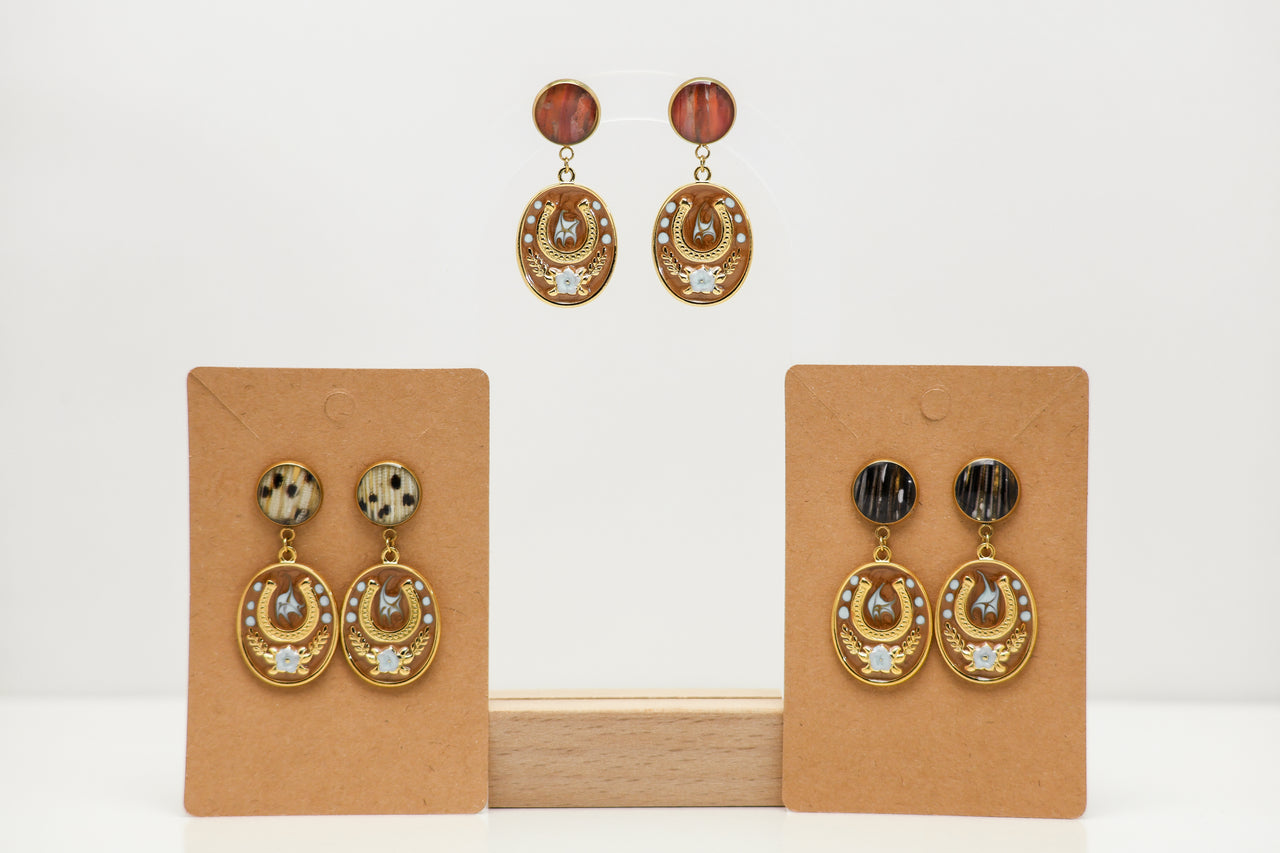 Pair of gold lionfish earrings on brown earring cards against a white background