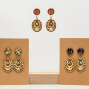 Pair of gold lionfish earrings on brown earring cards against a white background