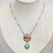 Necklace with a lionfish pendant and turquoise on a mannequin bust against a light background
