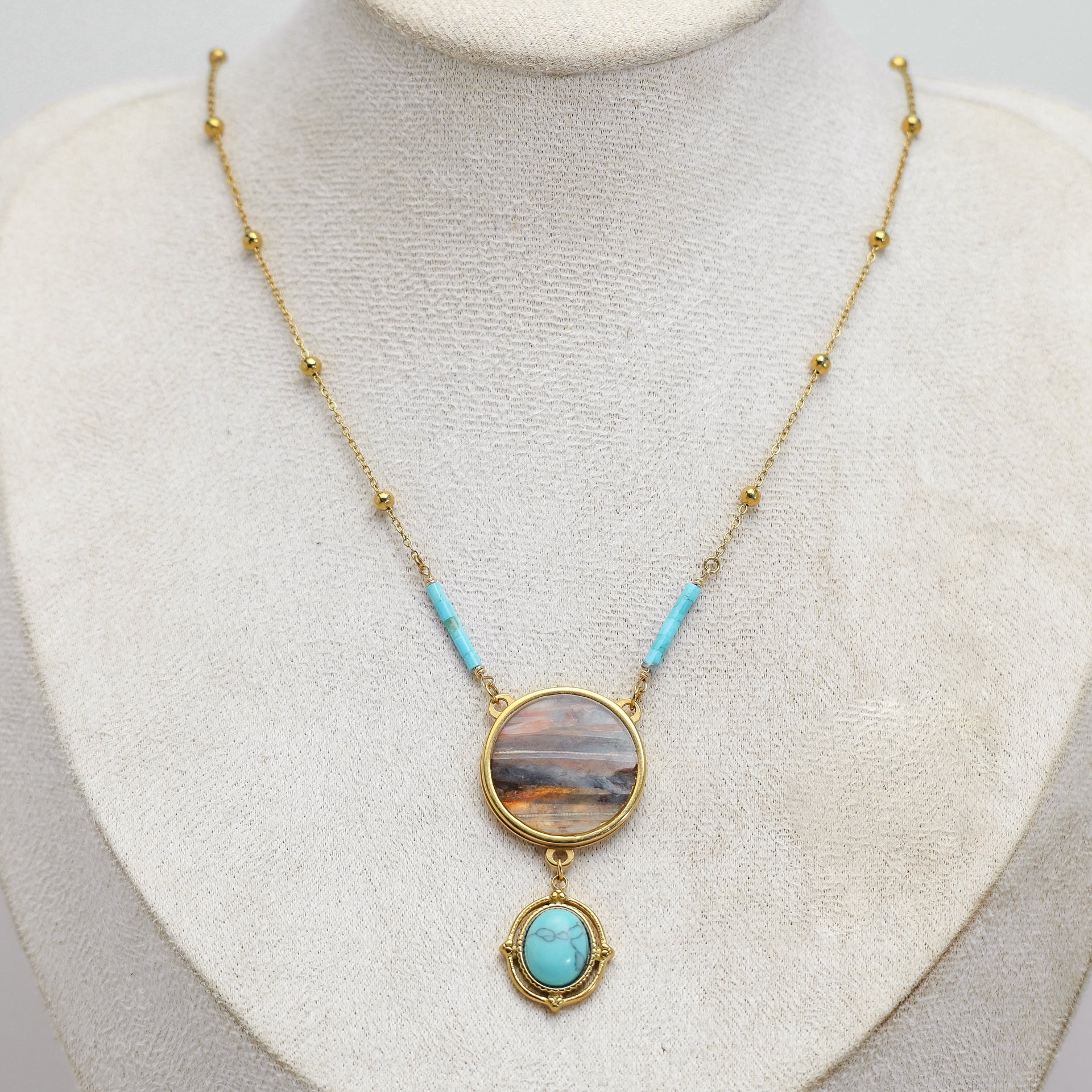 Necklace with a lionfish pendant and turquoise on a mannequin bust against a light background