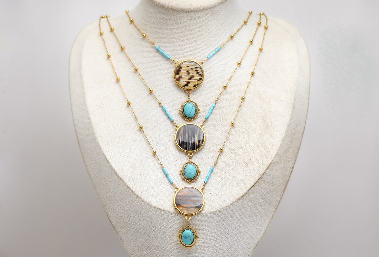 Necklace with turquoise stones and gold lionfish accents on a mannequin bust against a white background