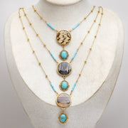 Necklace with turquoise stones and gold lionfish accents on a mannequin bust against a white background