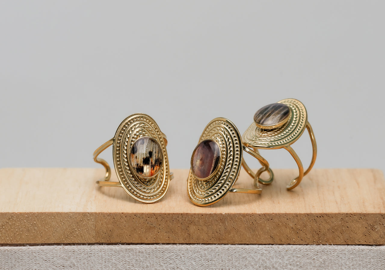 Three gold rings with embedded lionfish fins on a wooden surface