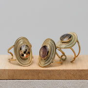 Three gold rings with embedded lionfish fins on a wooden surface