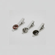Three silver tie clips with lionfish fin button on a light gray background