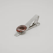 Silver tie clip with lionfish pectoral fin button on a light gray background