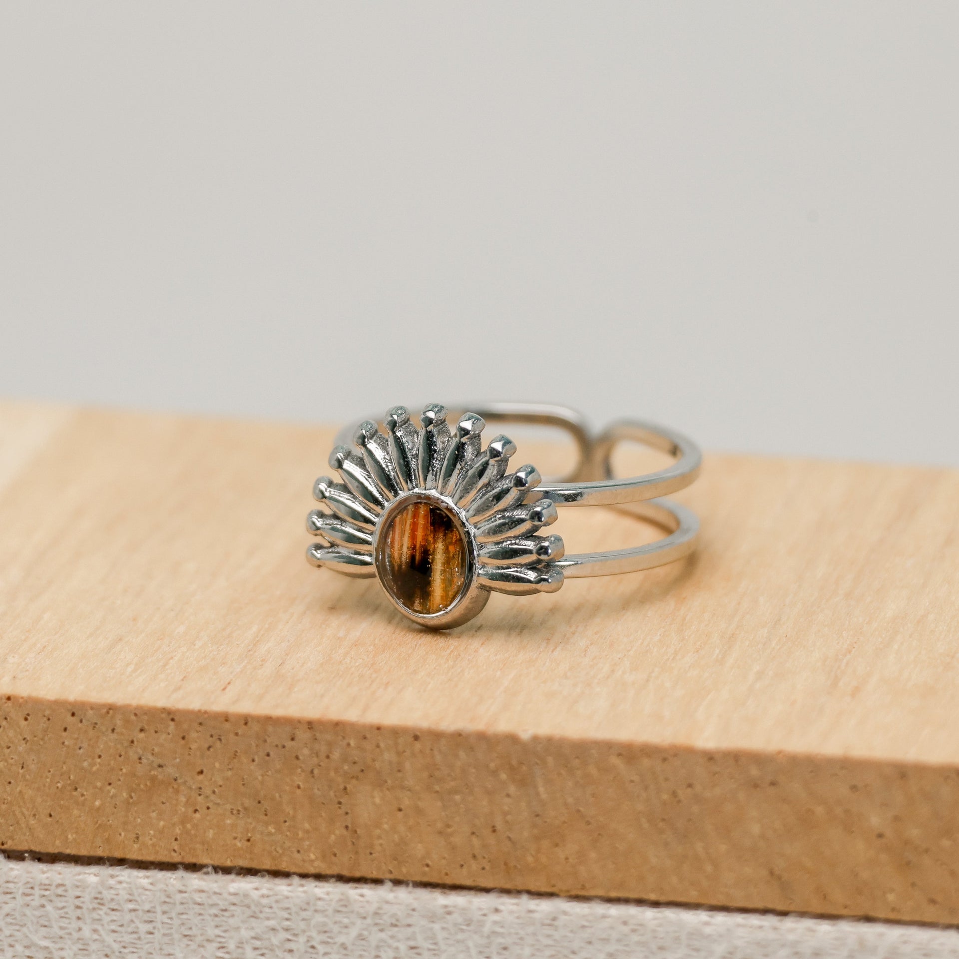 Silver ring with a lionfish fin on a wooden block