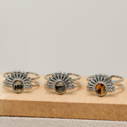 Three silver rings with lionfish fins on a wooden block against a gray background