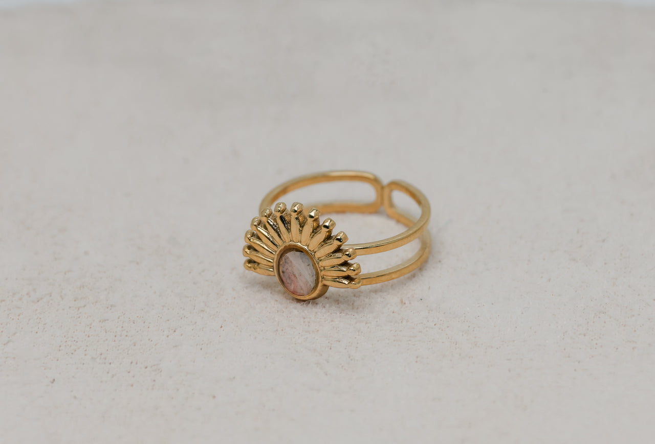Gold ring with a pink lionfish fin on a light gray background