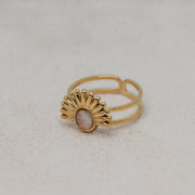 Gold ring with a pink lionfish fin on a light gray background