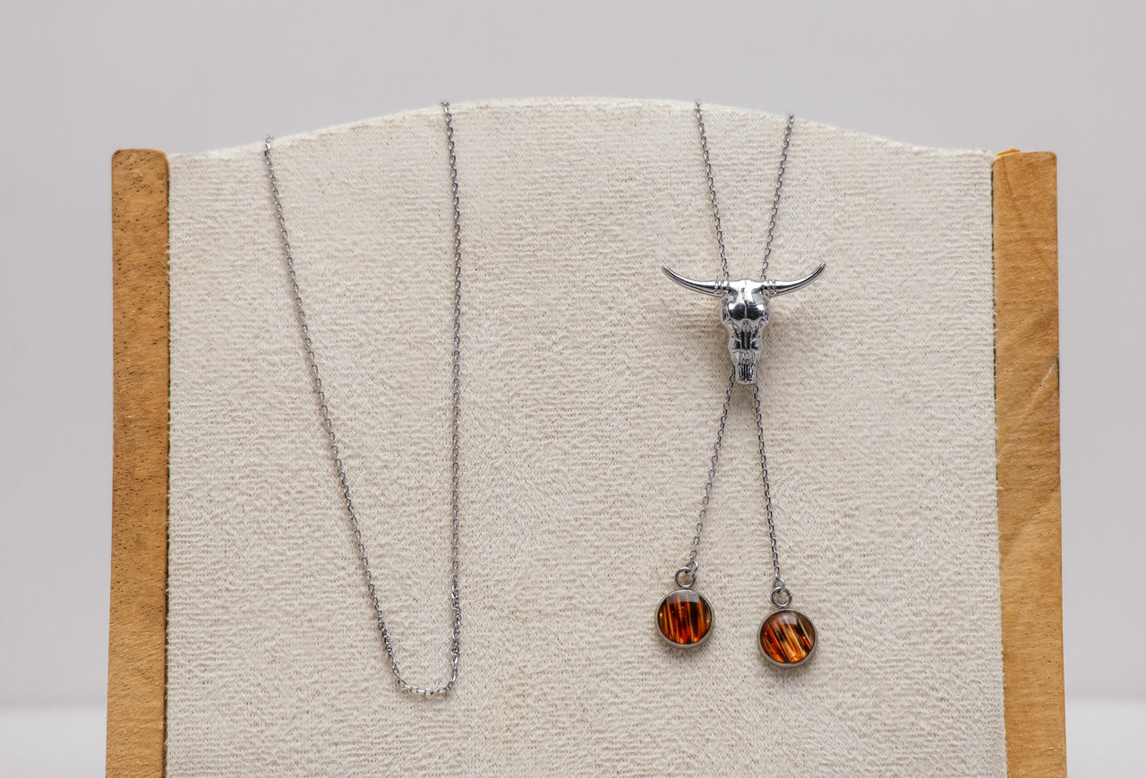 Necklace with pendant on a wooden stand against a gray background and lionfish fins