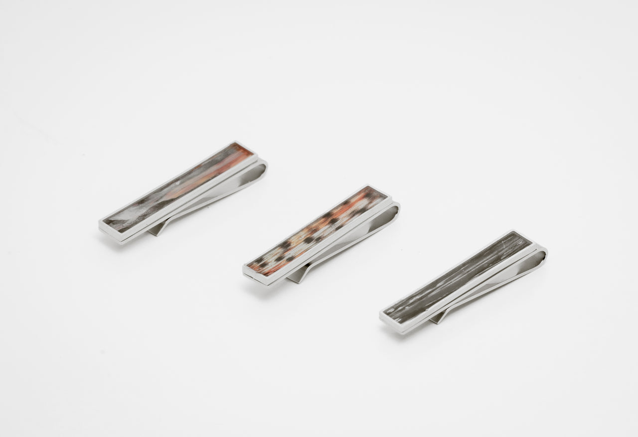 Three silver tie clips with lionfish inlay on a white background