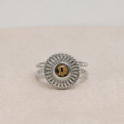 Silver ring with a circular lionfish design on a beige surface