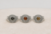 Three silver rings with embedded lionfish fins on a beige background