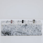 Three silver rings with a small vertical bar on white and black marble on a white background