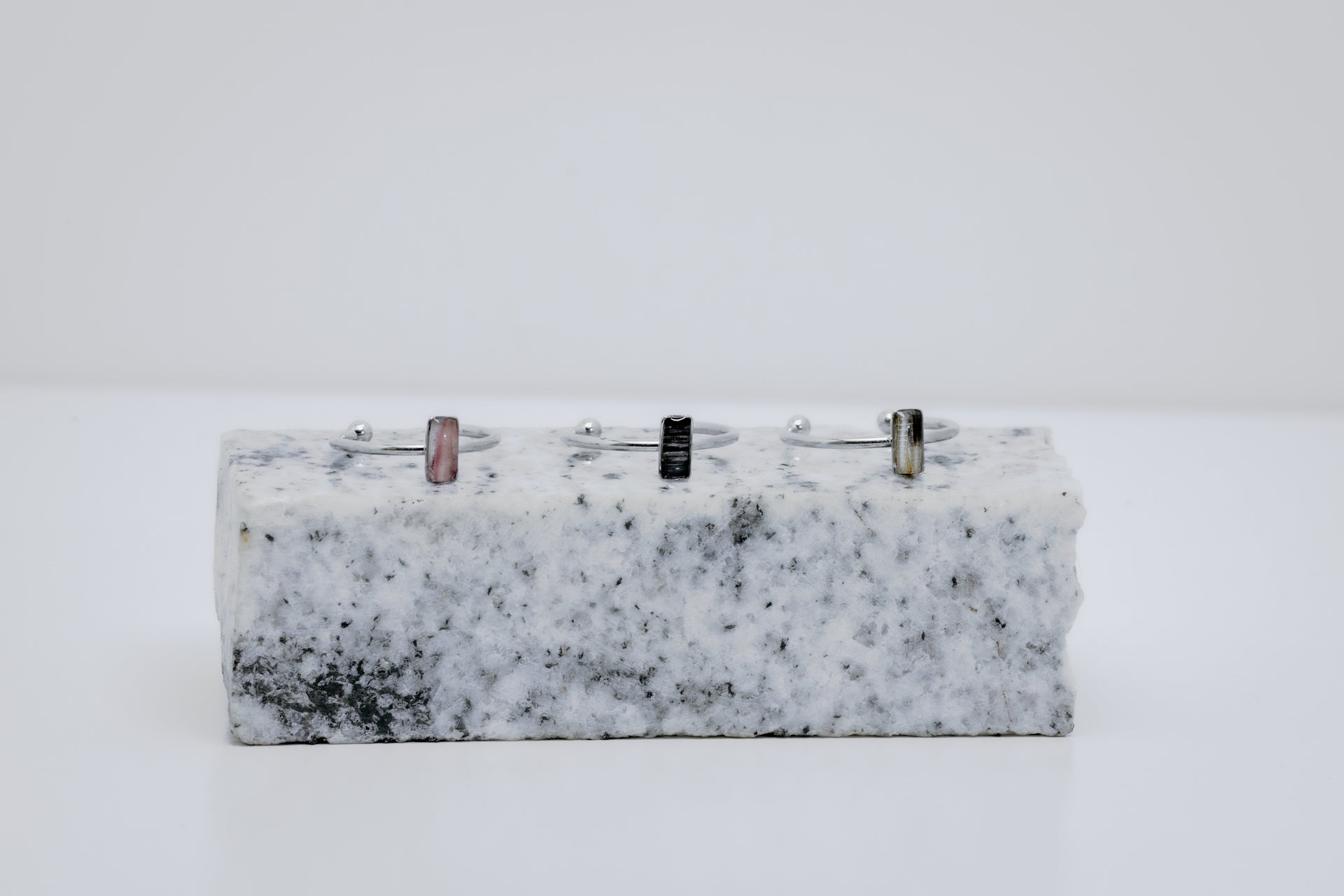 Three silver rings with a small vertical bar on white and black marble on a white background