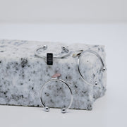 Three silver rings with a small vertical bar on white and black marble on a white background