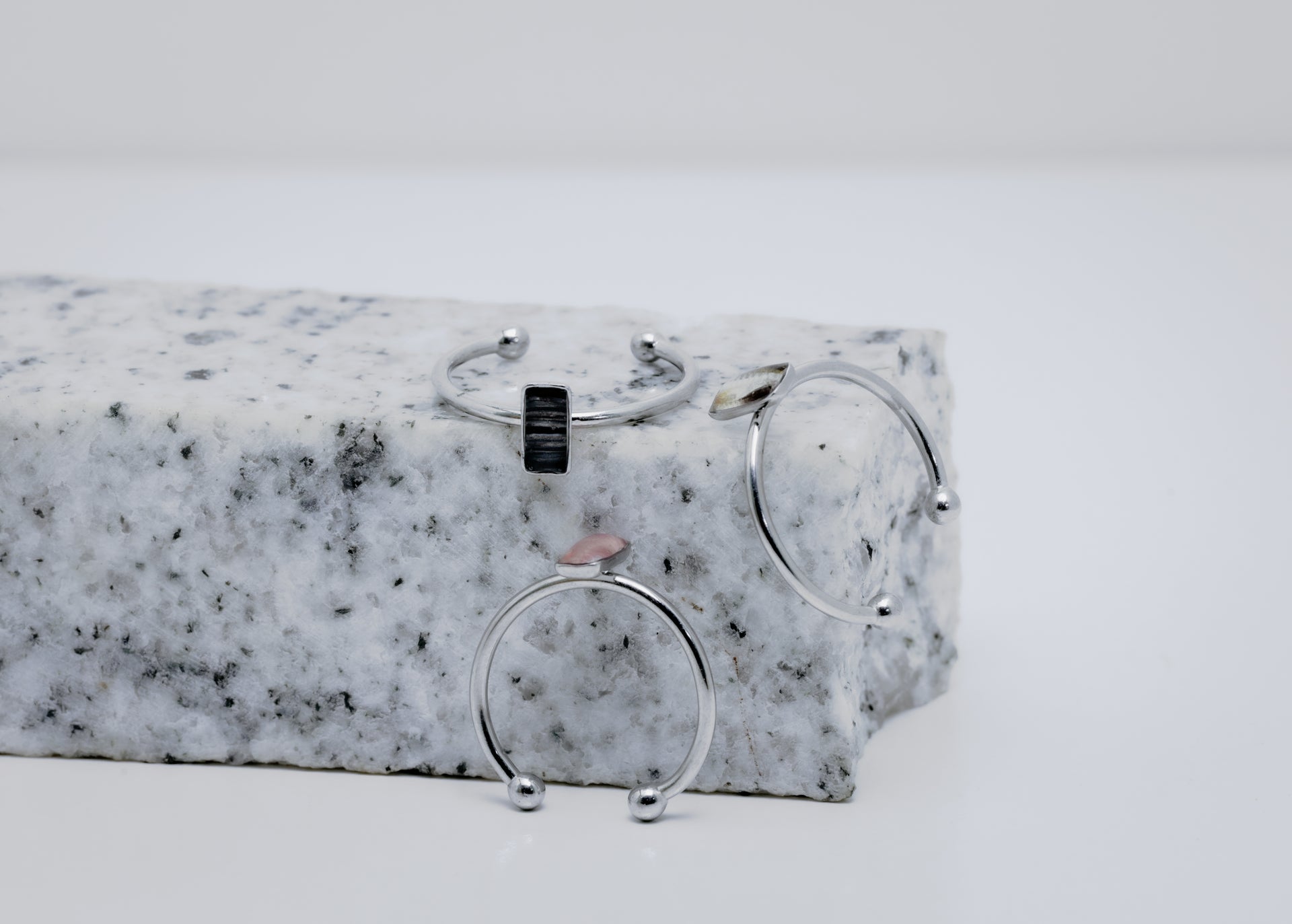 Three silver rings with a small vertical bar on white and black marble on a white background