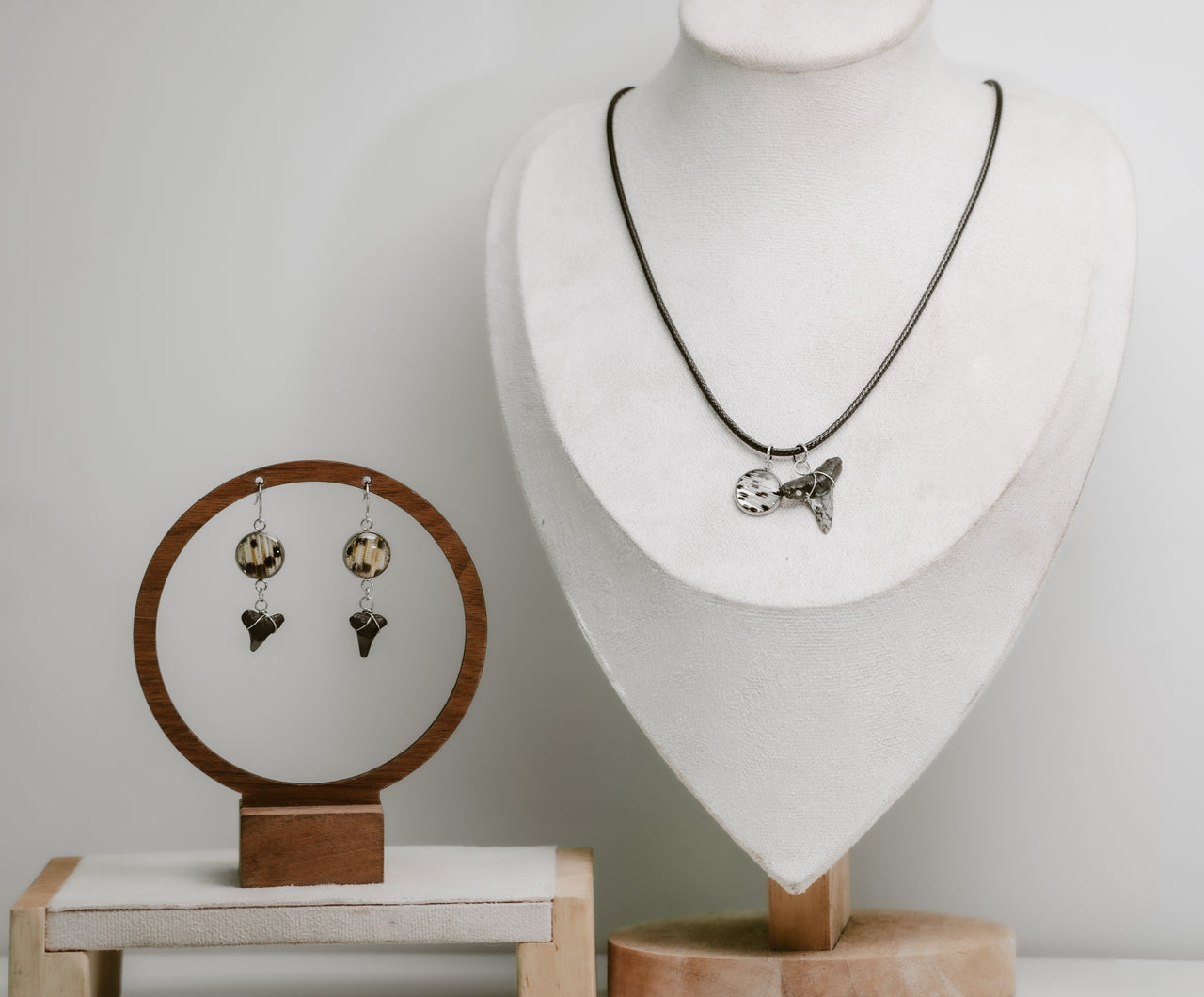 Jewelry set including a necklace and earrings displayed on mannequin and wooden stands.