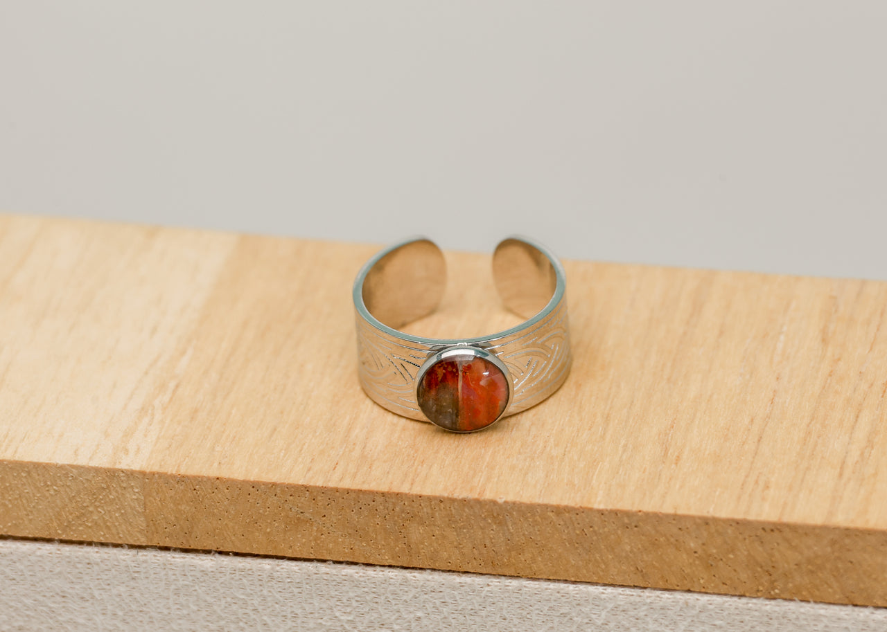 Silver bracelet with a red lionfish fin on a wooden surface