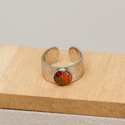 Silver bracelet with a red lionfish fin on a wooden surface