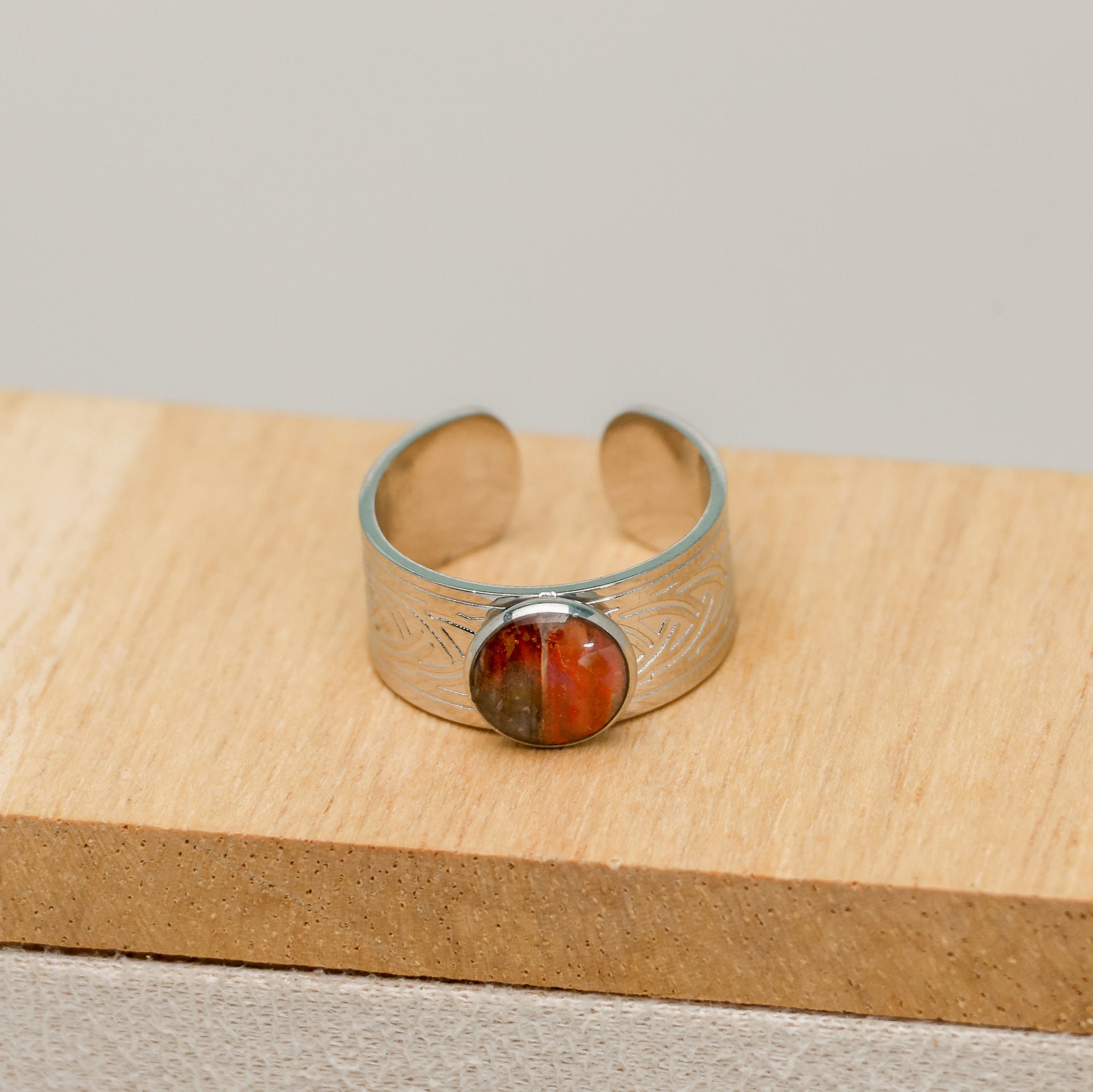 Silver bracelet with a red lionfish fin on a wooden surface