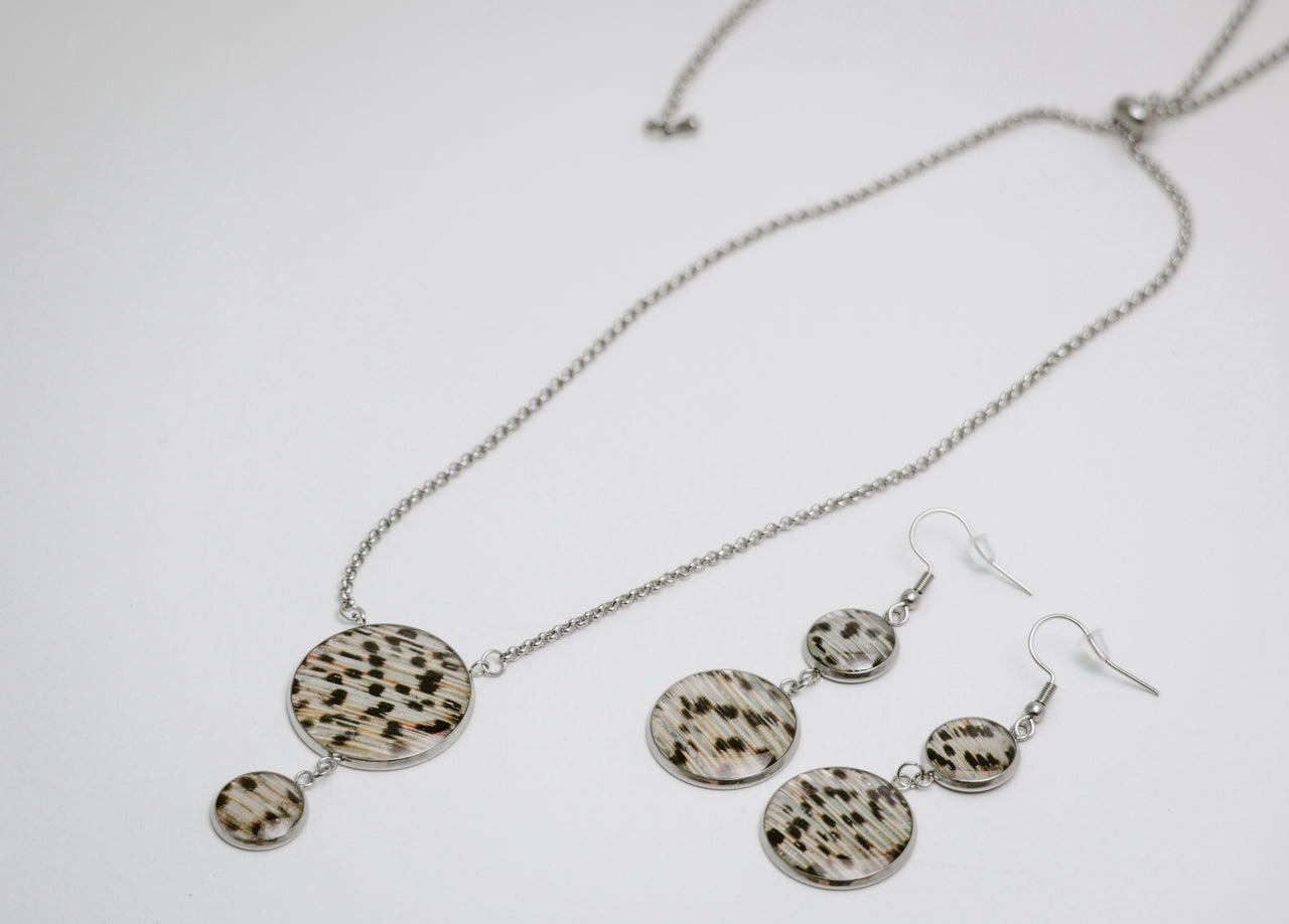 Silver Jewelry set with necklace and earrings featuring circular patterns on a white background