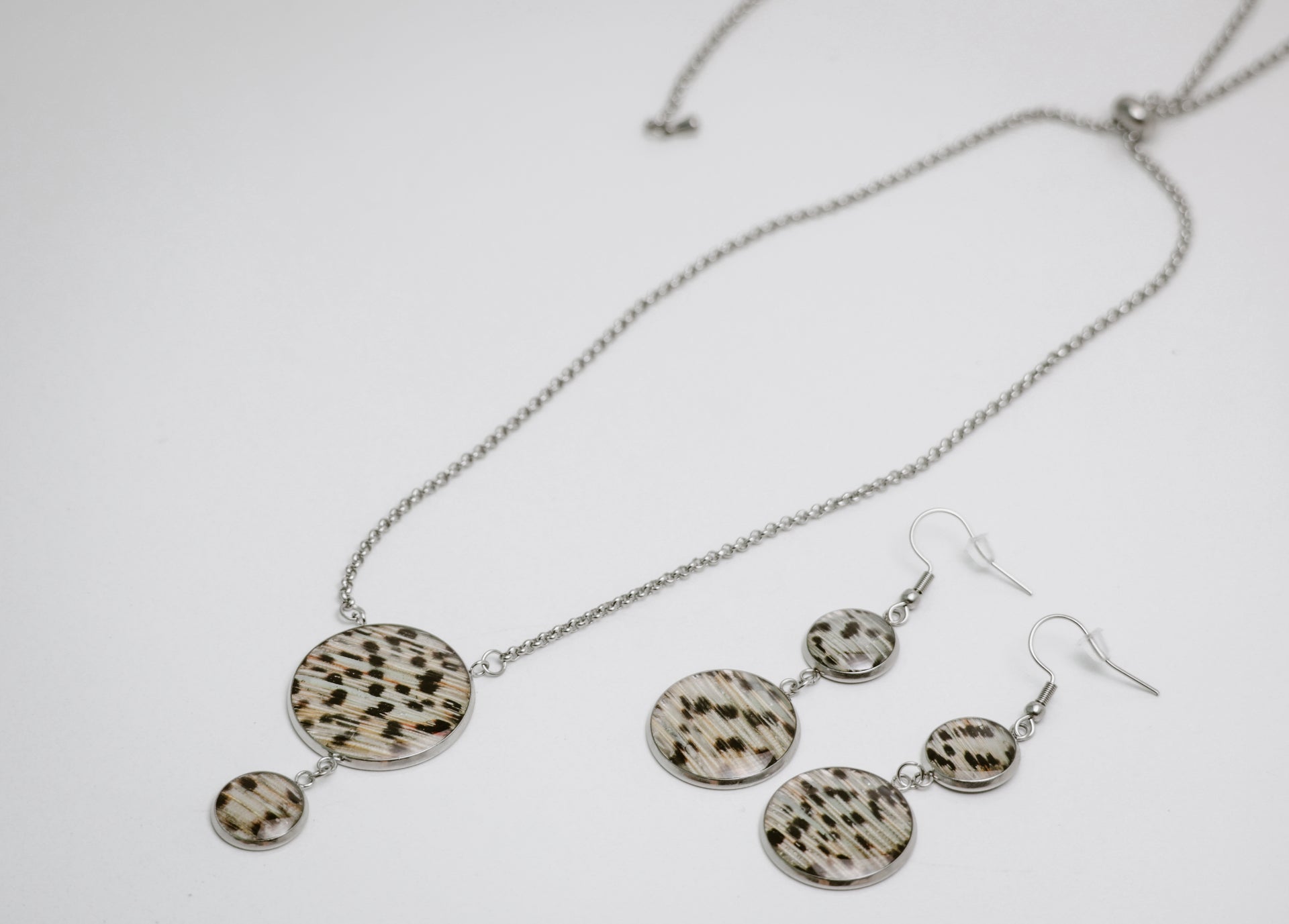 Silver Jewelry set with necklace and earrings featuring circular patterns on a white background