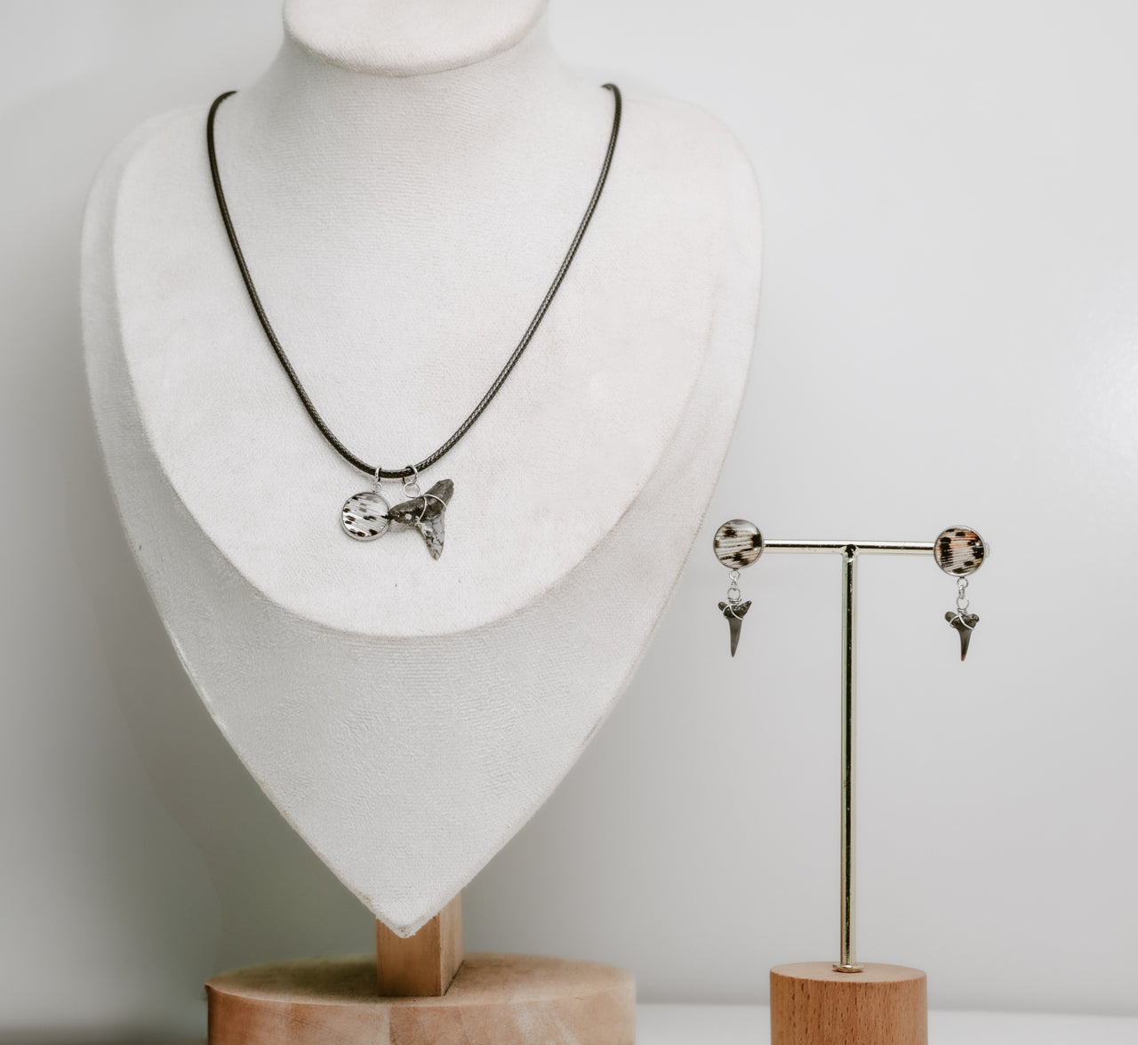 Jewelry set with necklace and earrings on a mannequin and stand against a white background