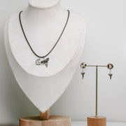 Jewelry set with necklace and earrings on a mannequin and stand against a white background