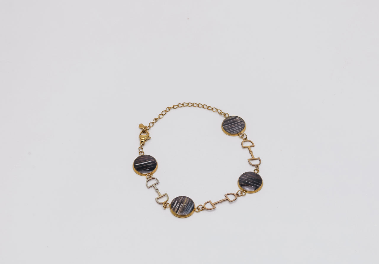 Bracelet with gold chain and dark lionfish fins on a light gray background