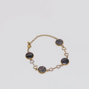 Bracelet with gold chain and dark lionfish fins on a light gray background