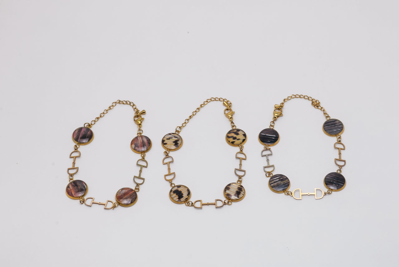 Three gold necklaces with lionfish fins on a light gray background