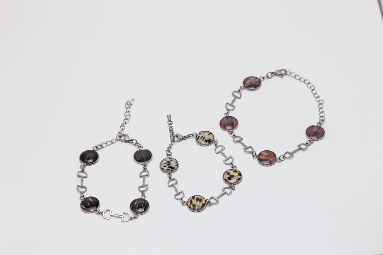 Three bracelets with dark lionfish fins on a white background