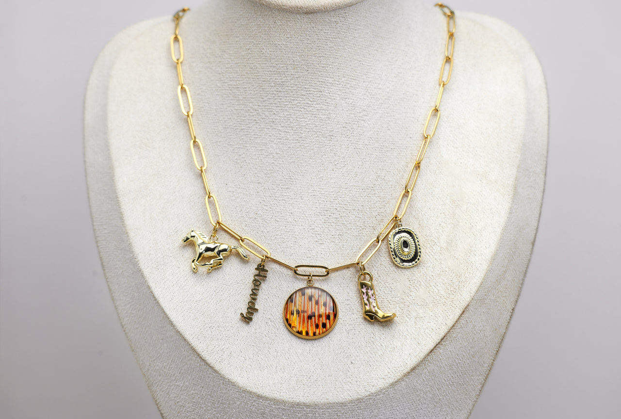 Gold necklace with western and lionfish charms on a white mannequin bust