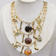 Gold necklace with various western and lionfish pendants on a mannequin bust against a gray background